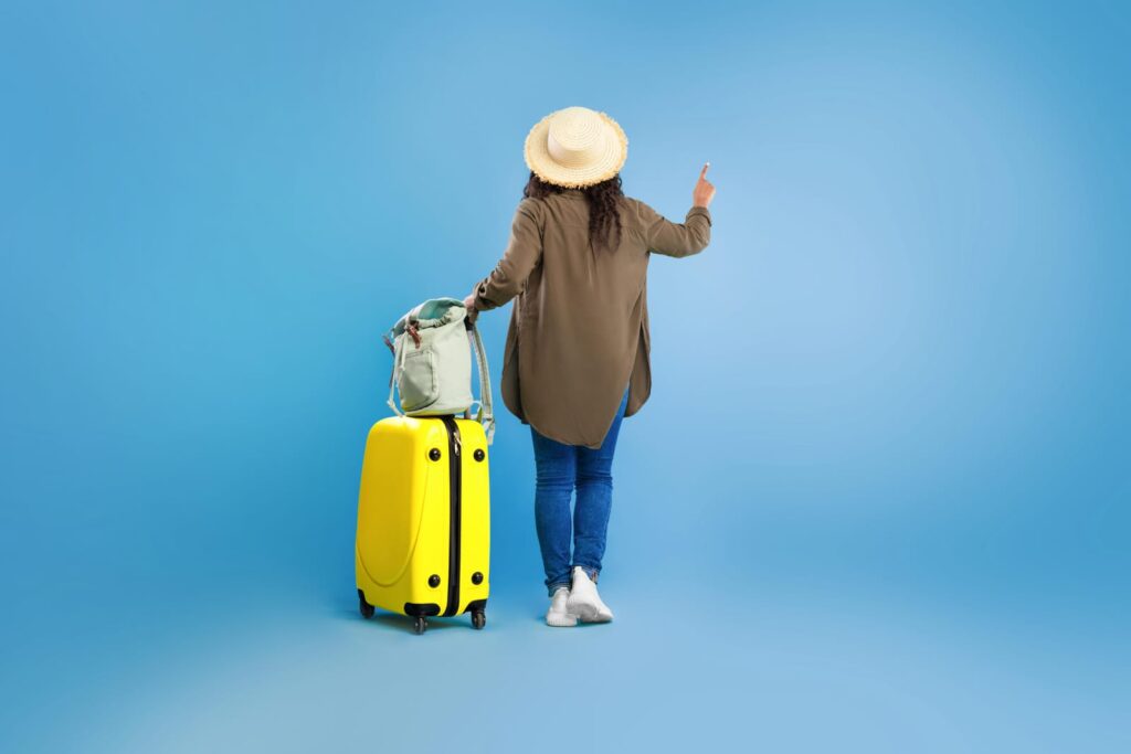 femme de dos avec valise, licence yayimages 104969422